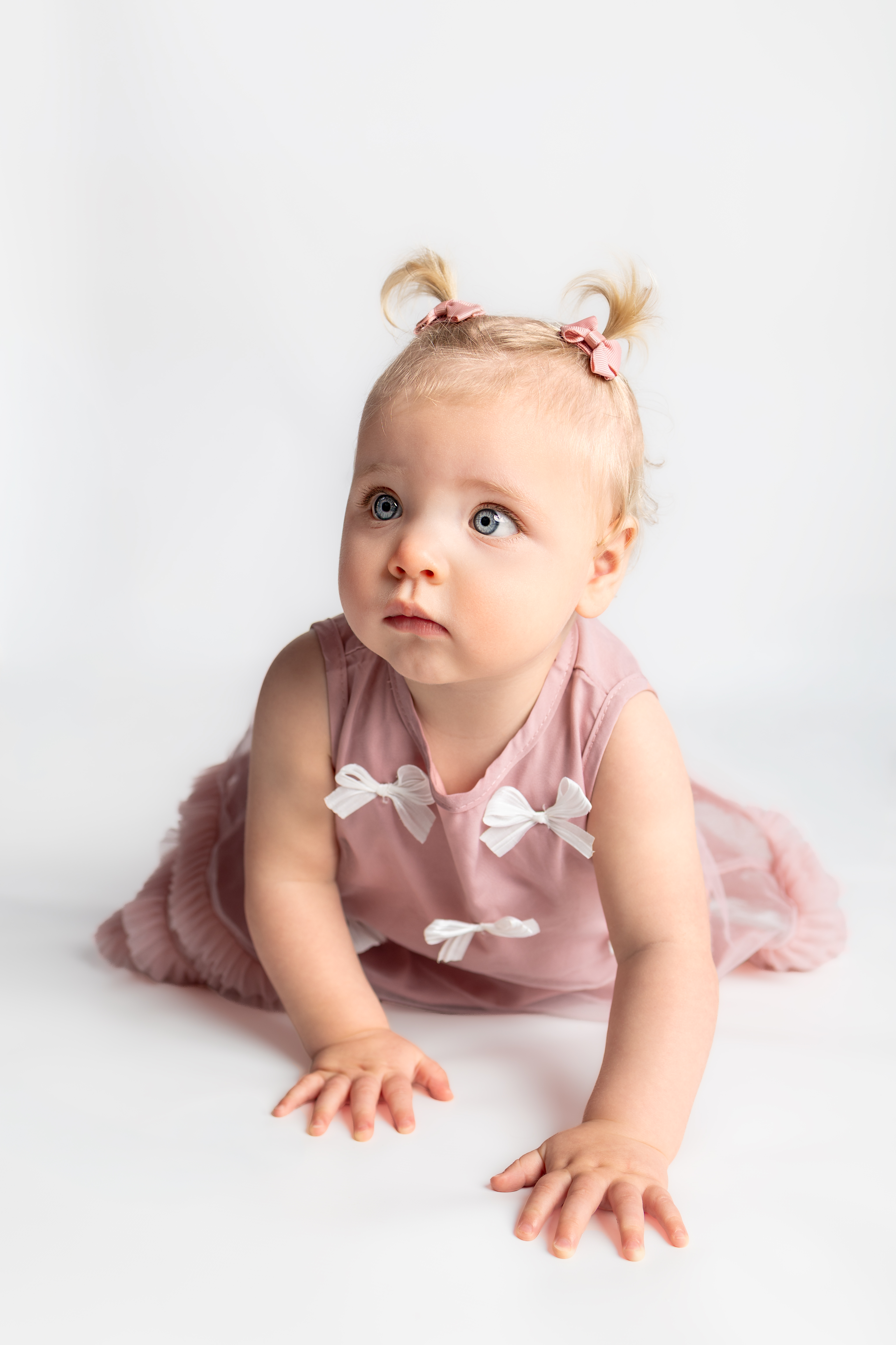 Toddler with pink hair bows and a pink dress in Jess’s studio